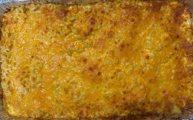 Mittie Mae’s Corner Market's baked macaroni and cheese with a golden-brown cheesy top in a foil pan.